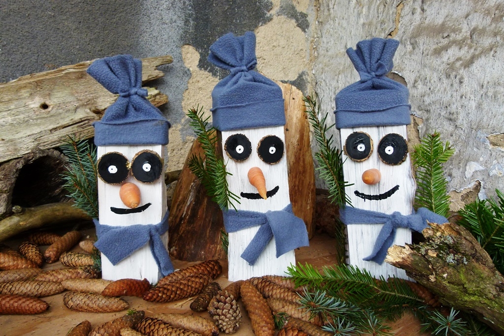 Trojice sněhuláků ze dřeva, naštípaného na topení do kamen