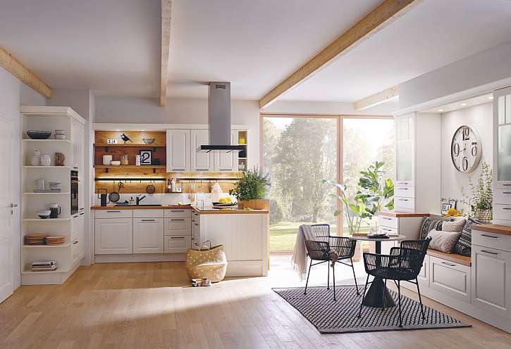 Velká a světlá kuchyň si žádá i světlý nábytek, doplněný dřevěnou podlahou a jemnými tóny slunce na dekoracích