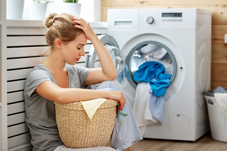 Unavená žena sedící u pračky 