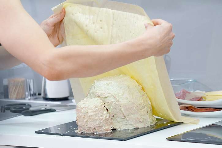 S pomocí pečicího papíru potáhněte prasátko lehce nahřátým plátkovým sýrem