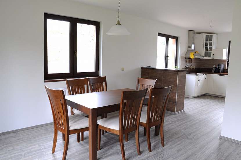 Jídelní stůl se židlemi v obývacím prostoru ladí s kuchyňskou deskou