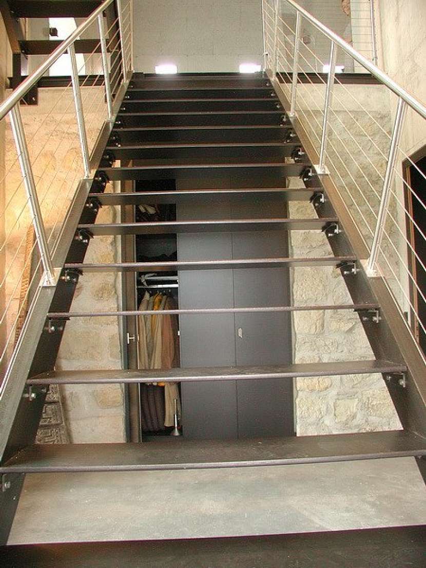 Kovové schodiště s nerezovým zábradlím prochází všemi patry bytu