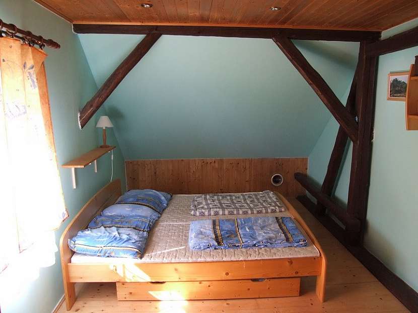 Modrá v kombinaci se dřevem sluší podkrovní ložnici i prostorné koupelně s oknem