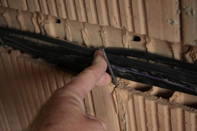 Kabely udrží na místě hřebík zatlučený do spáry ve zdivu