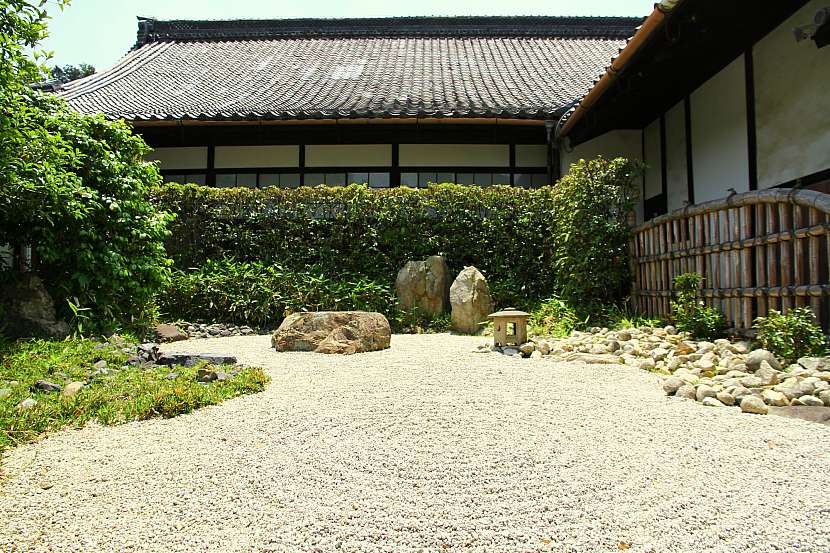 Jednoduchá kompozice vytvořená z kamenů a oblázků, doplněná japonskou lampou a zelení
