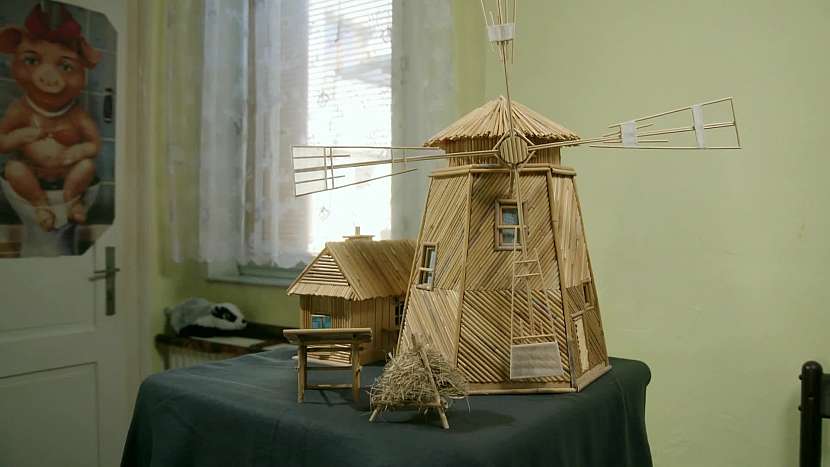 Miniaturní stavba větrného mlýna z rákosu, jehož lopatky pohání malý motůrek