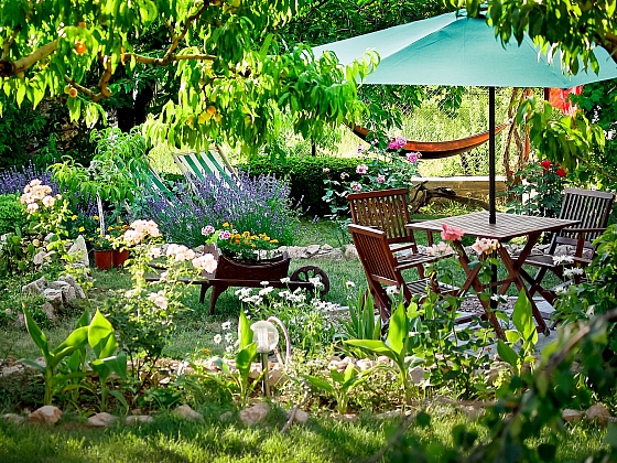 Slunečník u stolu dotváří pohodu uprostřed zahrady (Zdroj: depositphotos.com)