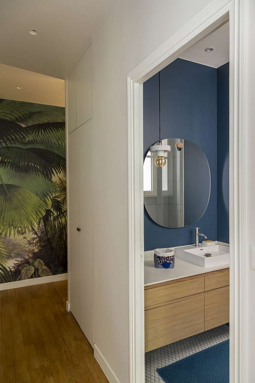 Koupelna je ryze funkční a moderní. Opět se v ní objevuje tmavomodrá barva v kombinaci s mramorovým obkladem a dřevodekorem na koupelnovém nábytku.