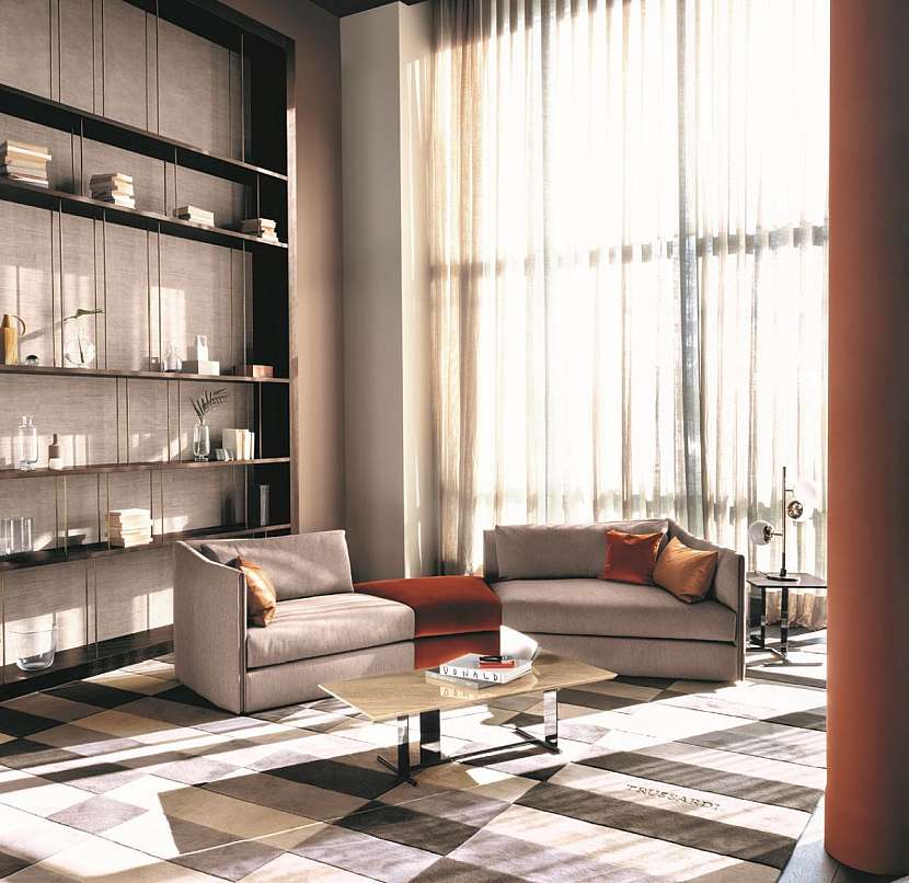 Vsazená barva a zajímavý geometrický koberec dělají místnost zajímavou, bez nich by to bylo fádní… také zlaté tenké vzpěry u polic dekorují. Pokud zlato snášíte – je velmi módní. Trussardi.