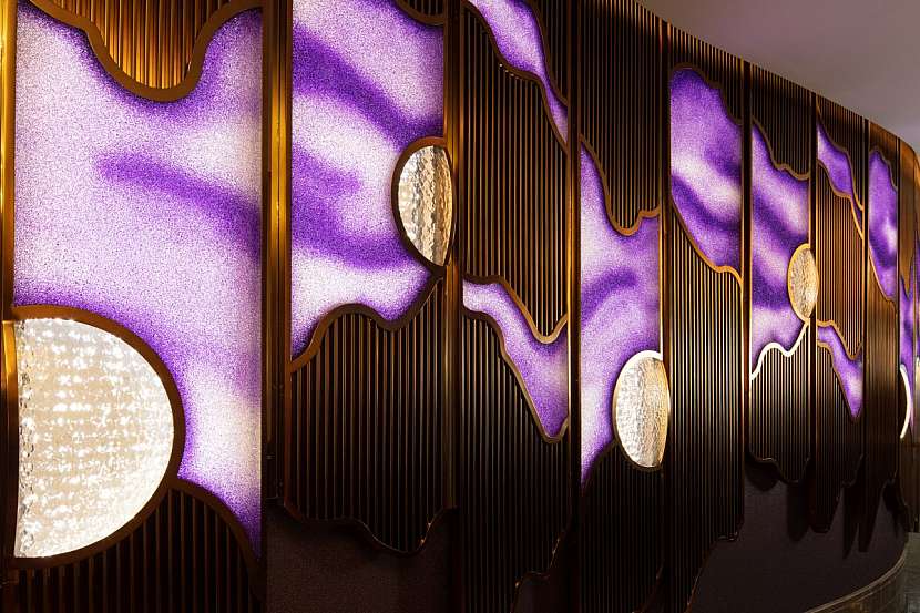 Více než sedm metrů vysoká zářivě fialová křišťálová stardustová zeď vítá hosty baru a restaurace Ossiano.