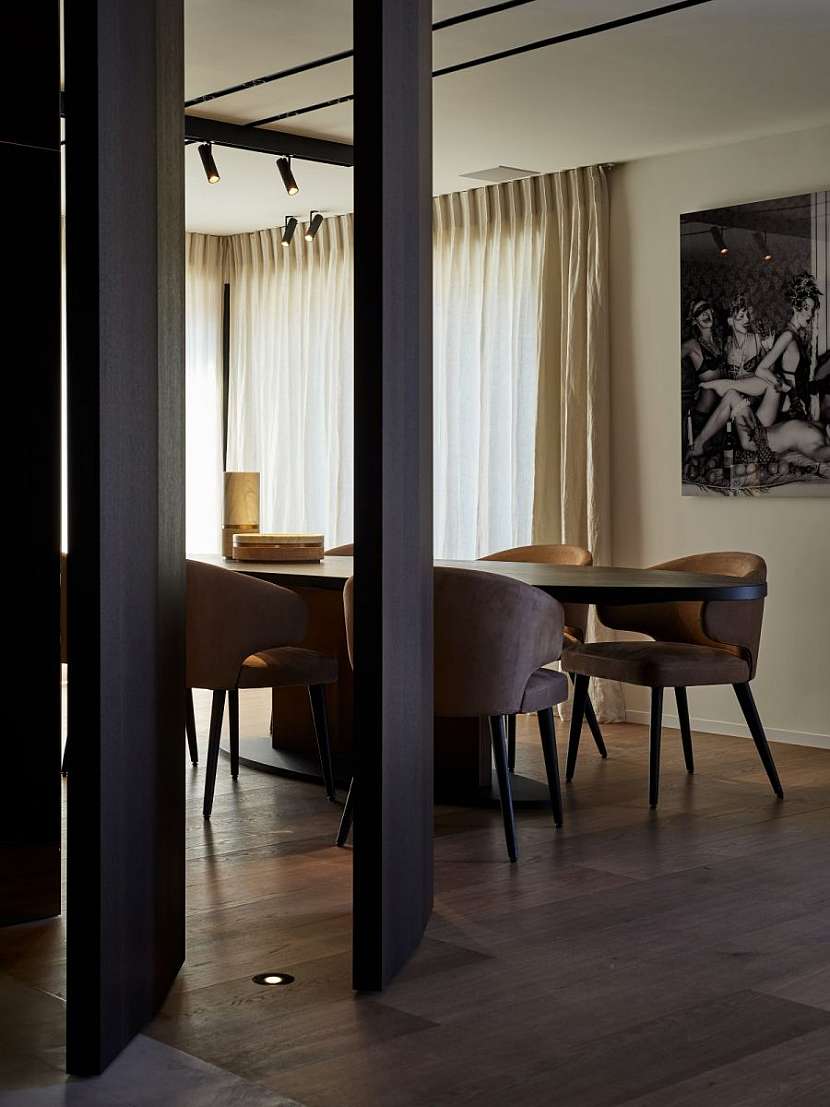 Dřevěná podlaha propojuje kuchyň s obývacím prostorem a naznačuje kontinuitu mezi jednotlivými částmi domu.