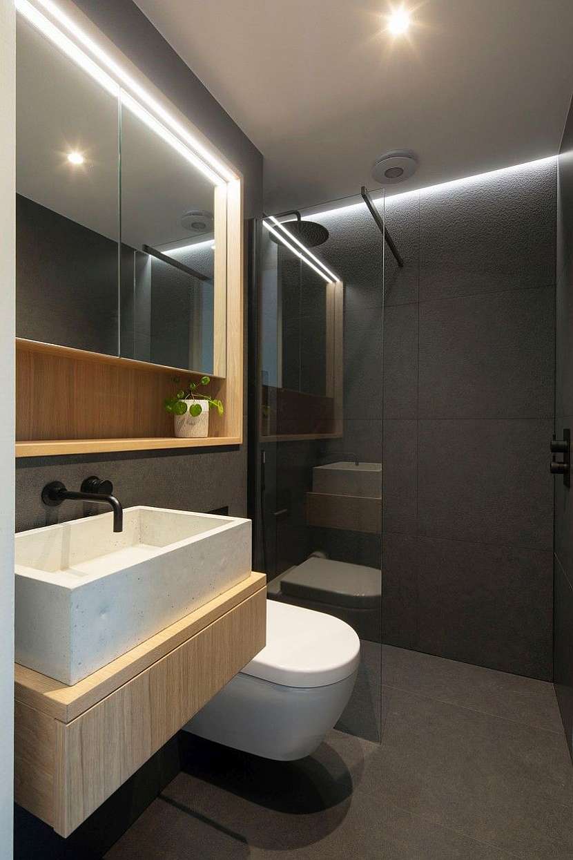 Koupelna je zařízena v tmavých  barvách, které doplňuje přírodní dřevo.