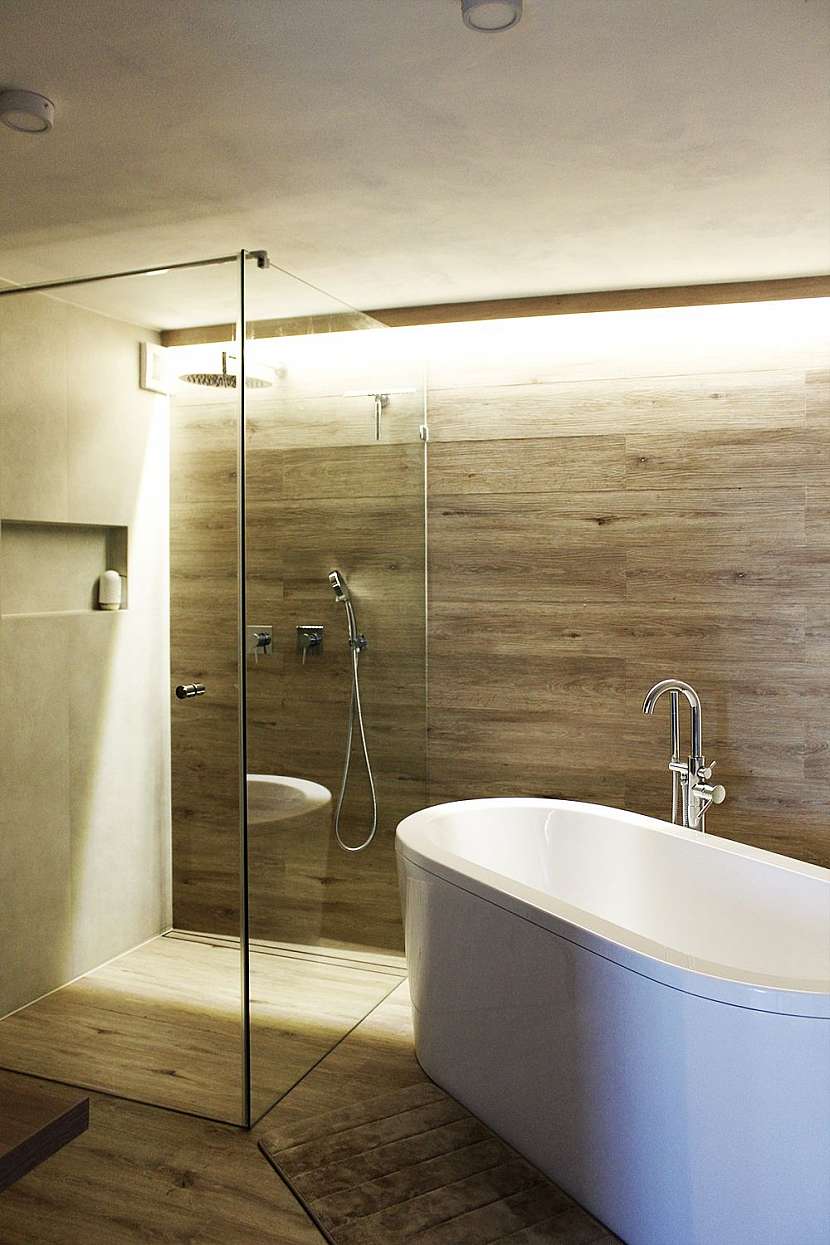 Koupelna disponuje sprchou splývající s podlahou, volně stojící vanou, dvěma umyvadly a toaletou.