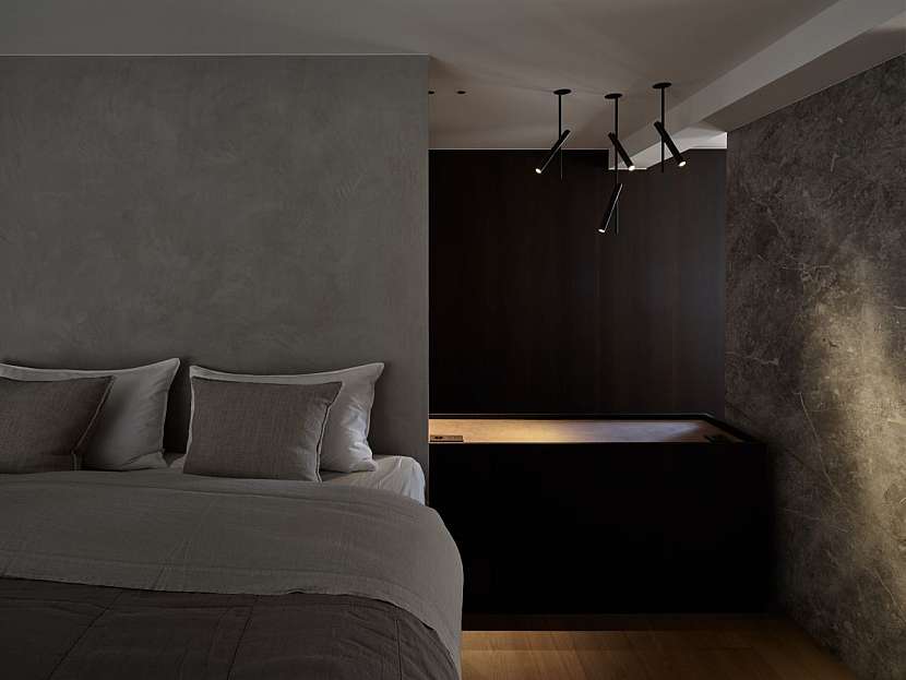 Ložnice v uklidňujících šedých tónech připomíná luxusní hotelové apartmá.