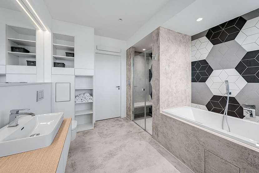 Hlavní koupelna je prostorná a je v ní vše, co obyvatelé potřebují – dvě umyvadla, vana a sprchový kout.