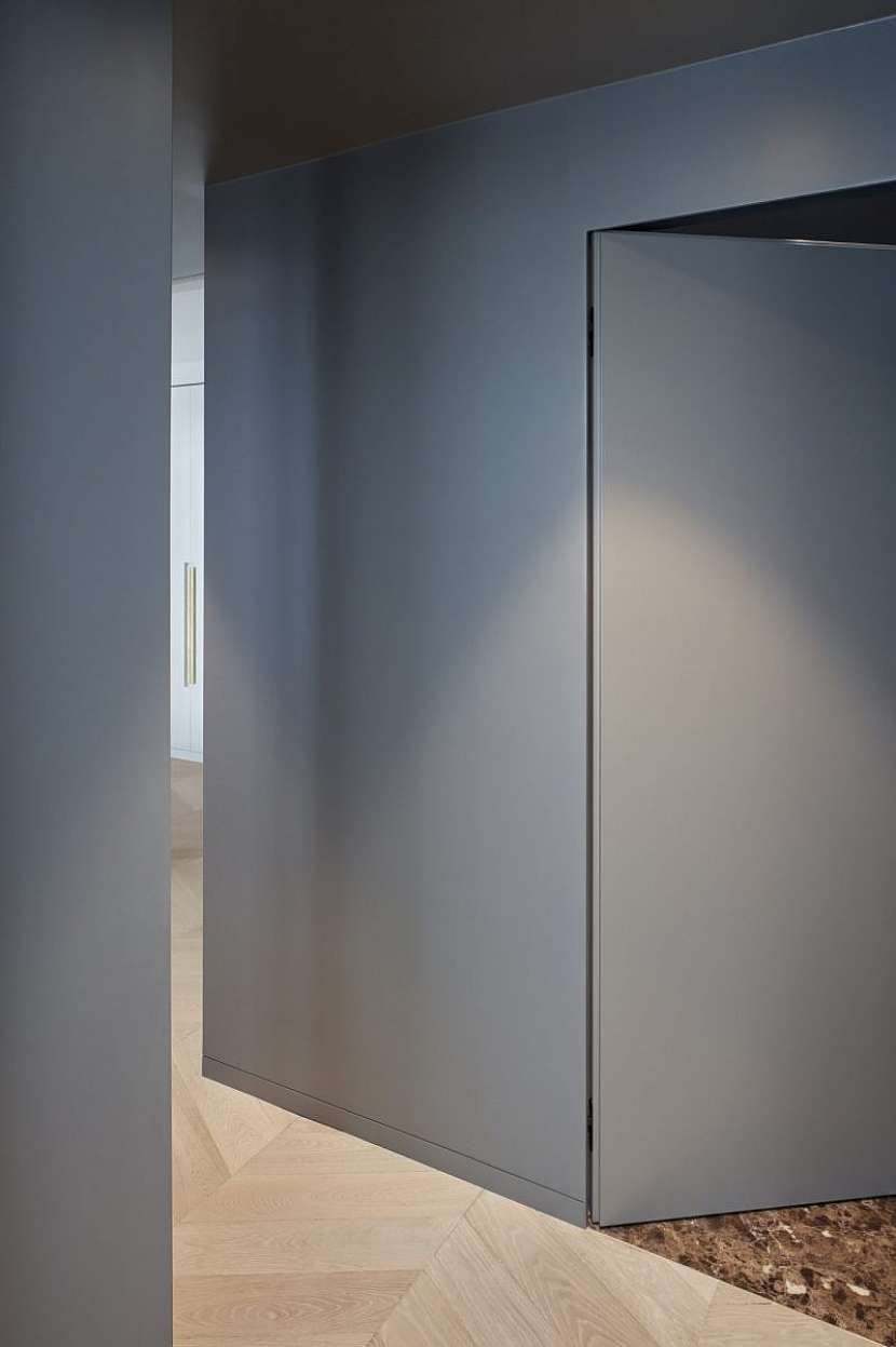 Pokoj pro hosty a tmavě šedé skříně se skrytými dveřmi.