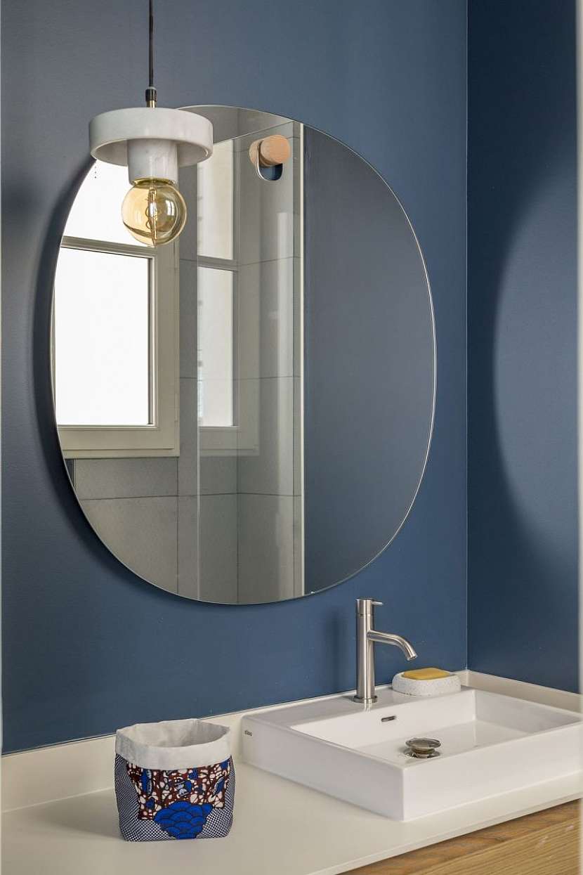 Koupelna je ryze funkční a moderní. Opět se v ní objevuje tmavomodrá barva v kombinaci s mramorovým obkladem a dřevodekorem na koupelnovém nábytku.
