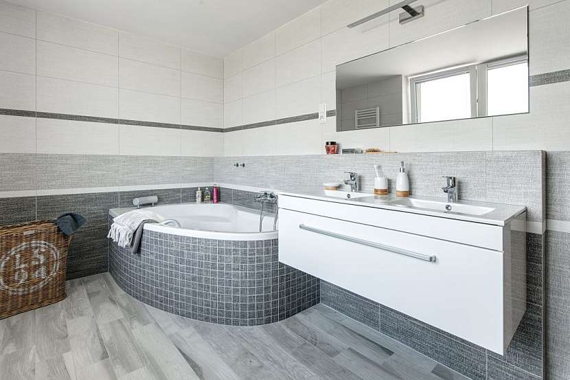 Koupelna v patře domu je vybavená rohovou vanou, sprchovým koutem a dvojumyvadlem.