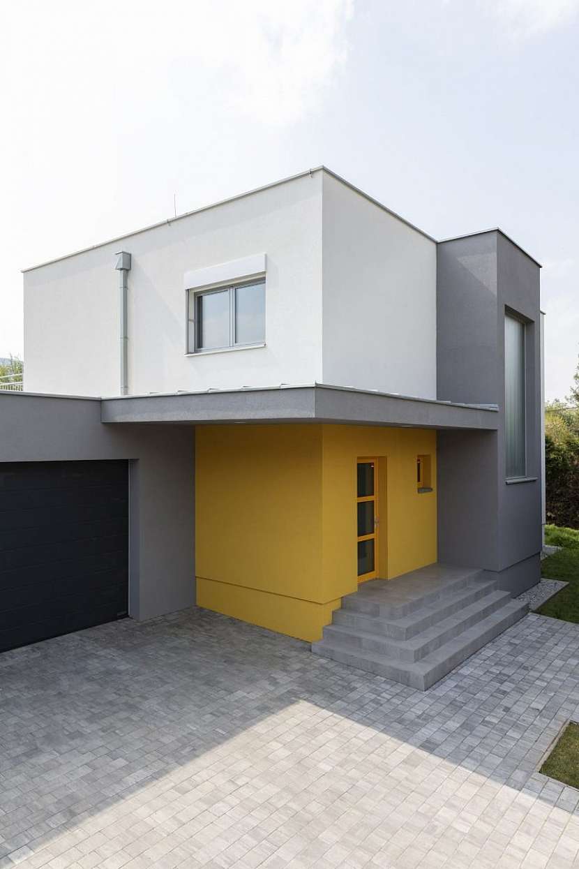 S okolím kontrastuje žlutý vstup do domu.