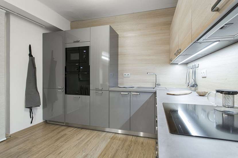 Nová kuchyně kombinuje šedou barvu a dřevo.