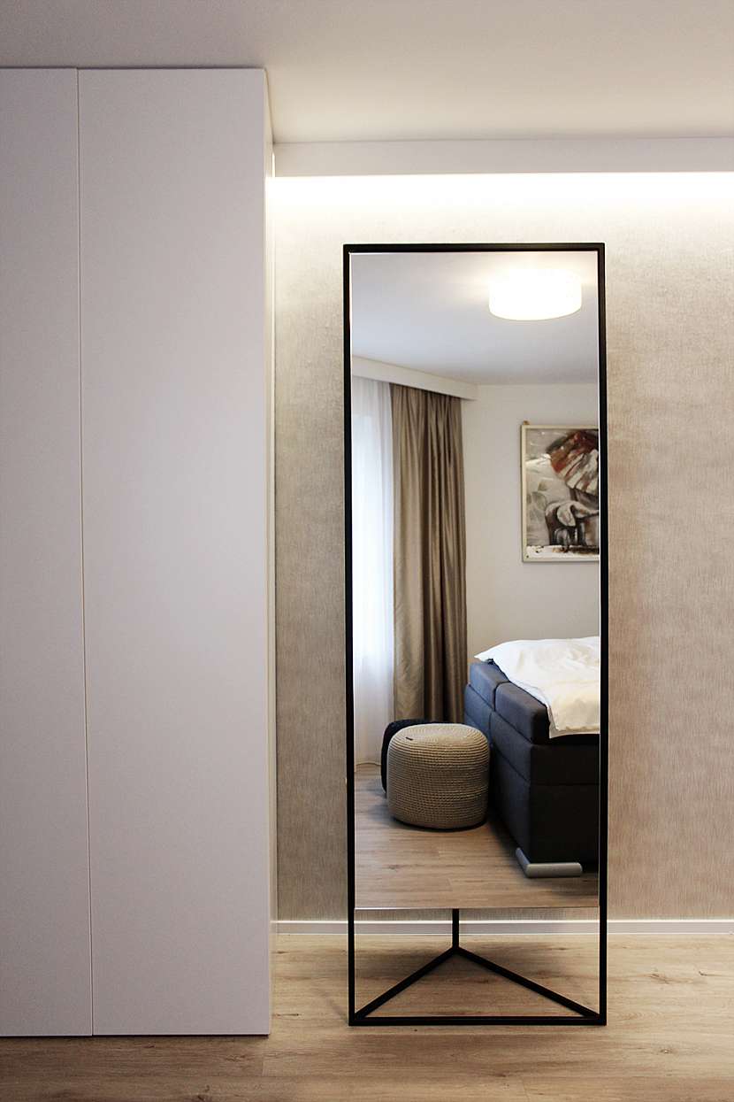 V prostoru vynikají luxusní doplňky z dílny české značky Demarco design - vysoký odkládací panel na oblečení se zrcadlem a měkké pufy jako útulné sezení u okna.