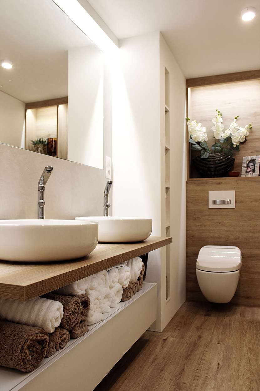 Koupelna disponuje sprchou splývající s podlahou, volně stojící vanou, dvěma umyvadly a toaletou.
