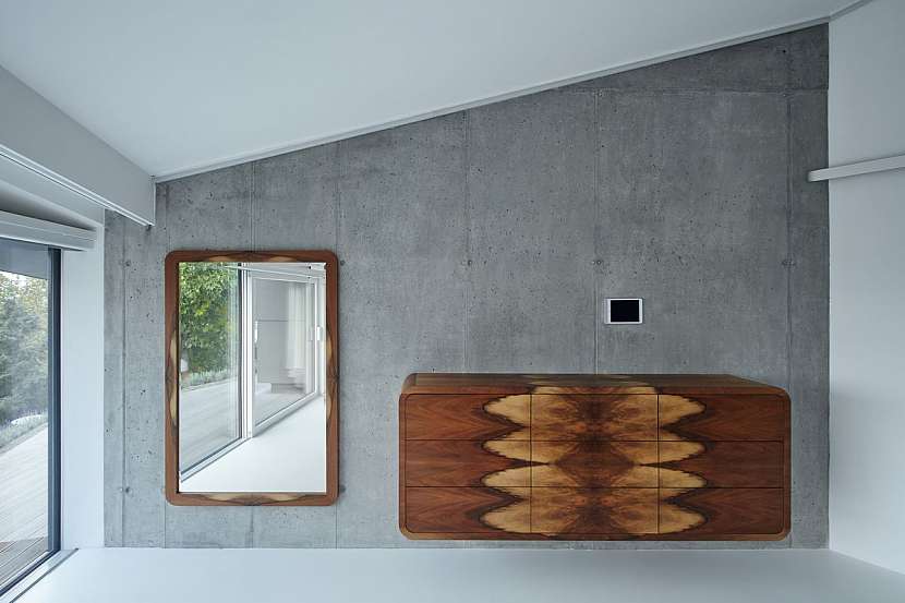 Vedle zářivě bílé a pohledového betonu se v domě objevuje i dřevo s výraznou kresbou.
