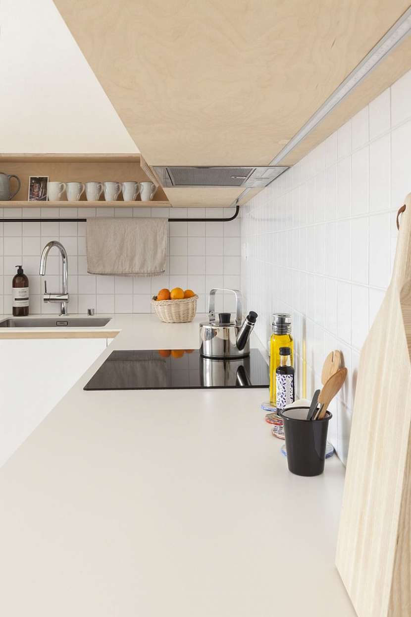Rohová bílá kuchyň je opět velmi puristická, ale nanejvýš funkční a nabízí nejen dostatek úložného prostoru, ale i pohodlnou pracovní plochu. .