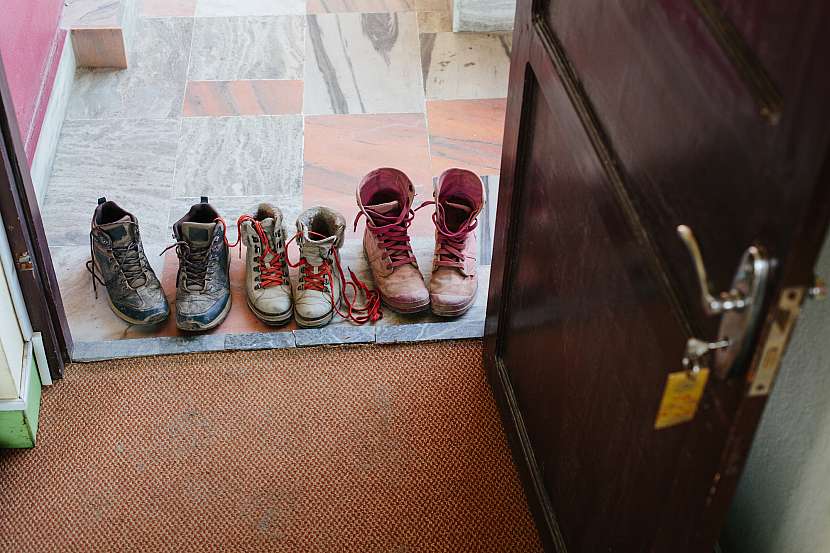 Špinavé zablácené boty na prahu u dveří a koberec