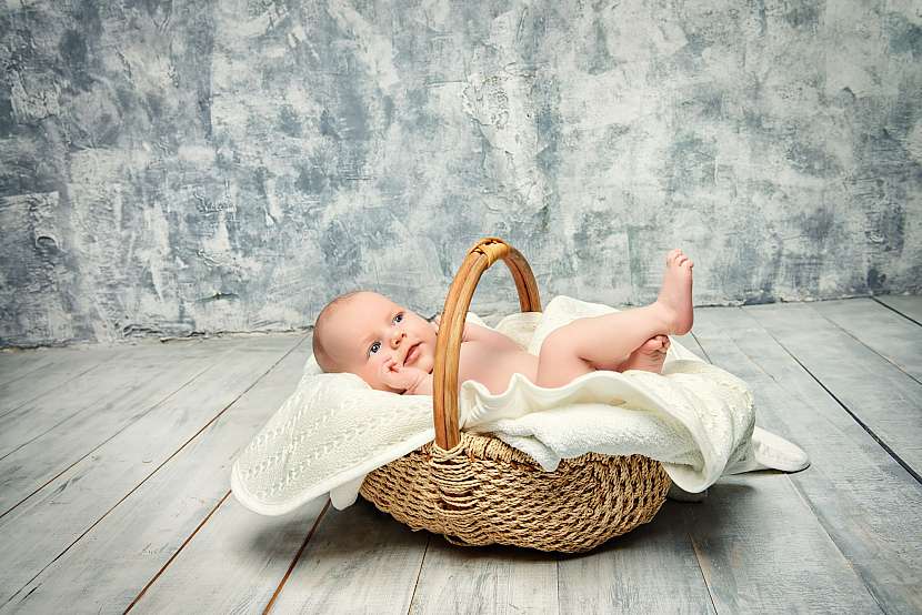 Malé dítě v košíku na dřevěné podlaze