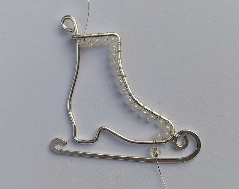 V místě, kde chcete upevnit nůž k přední části podrážky, navlékněte na drátek rokajl se stříbrným průvlekem