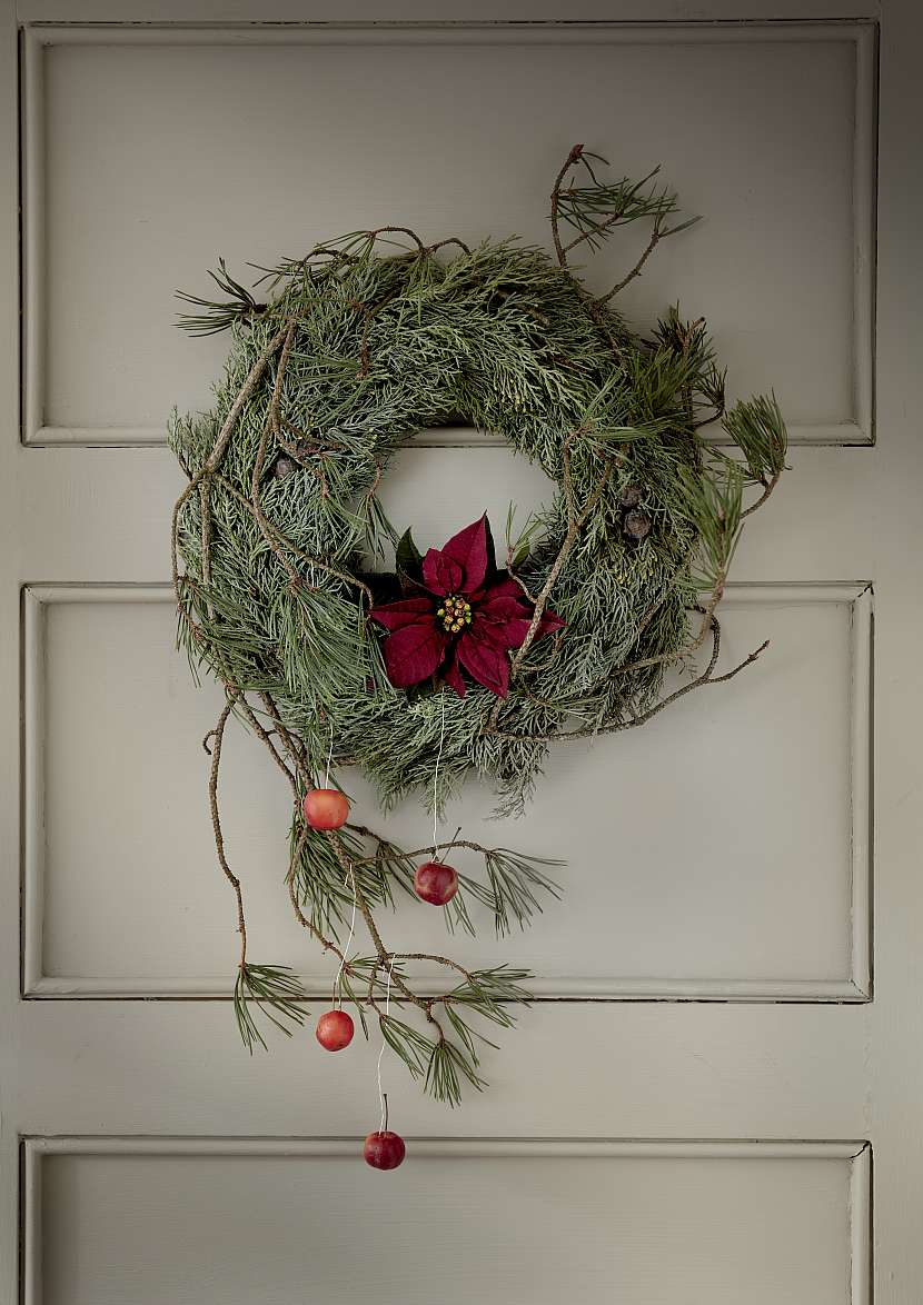 Cypřišový věnec zdobený dlouhými borovicovými větvemi se díky řezané červené vánoční hvězdě promění v krásnou vánoční výzdobu