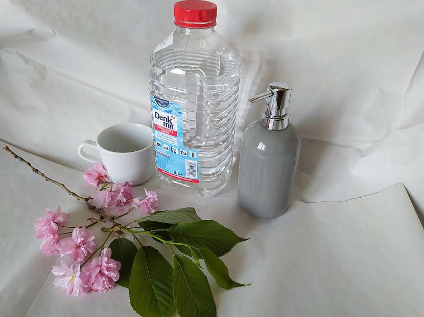 Destilovaná voda, šálek a dávkovač na mýdlo s třešňovou větví