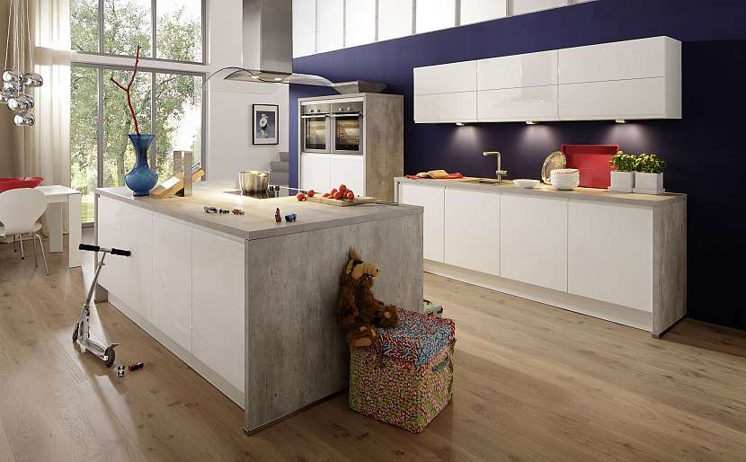 Dřevěná podlaha a bílá kuchyňská linka jsou doplněny výraznou tmavou stěnou za linkou