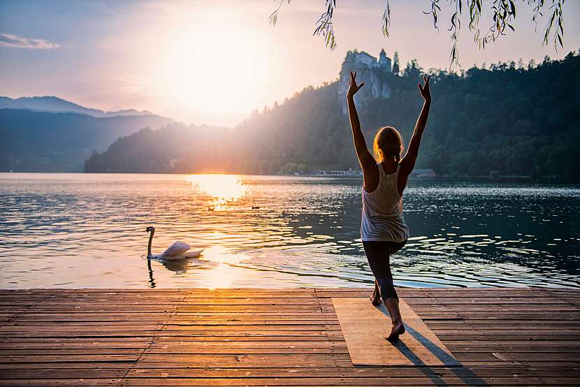 Žena cvičí jógu při východu slunce