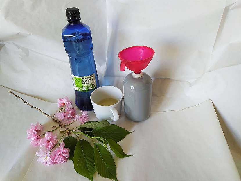 Nádoba na mýdlo s trychtýřem, hrnek s kastilským mýdlem, modrou lahví a třešňovou větví
