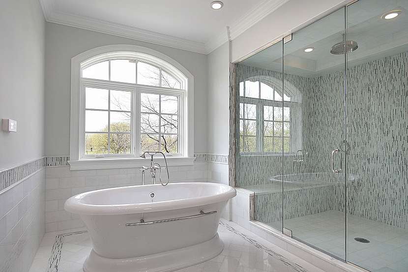 Koupelna v bílé barvě s velkým sprchovým koutem a volně stojící vanou