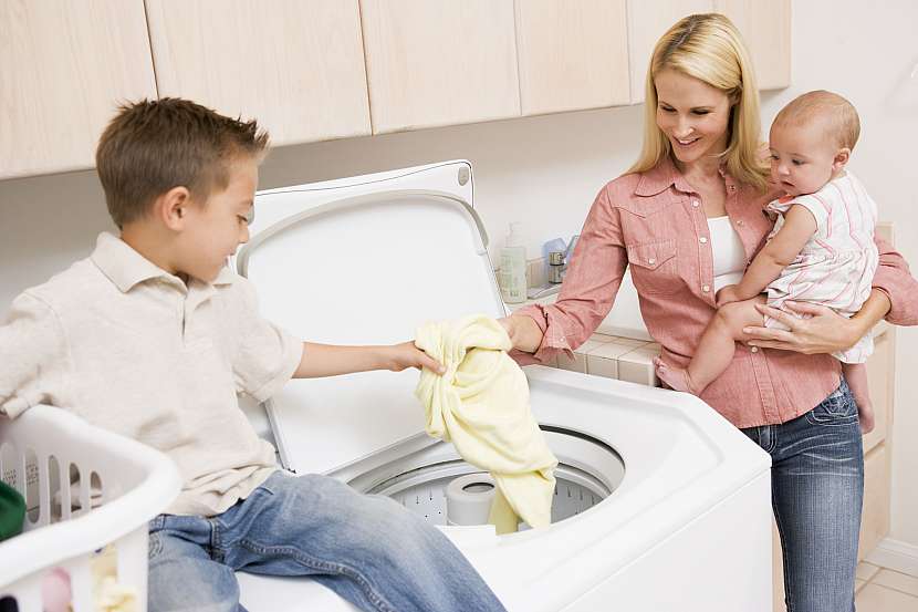 Matka s dvěma dětmi vytahují prádlo z pračky