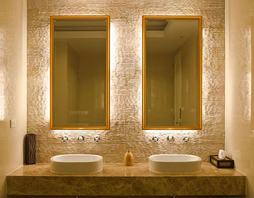 Zrcadla ve zlatém rámu v koupelně se dvěma umyvadly