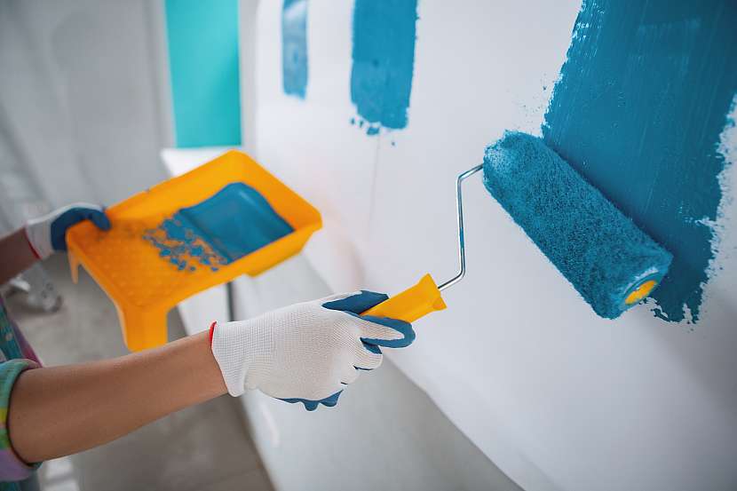Záběr na ruku malující válečkem stěnu na modro
