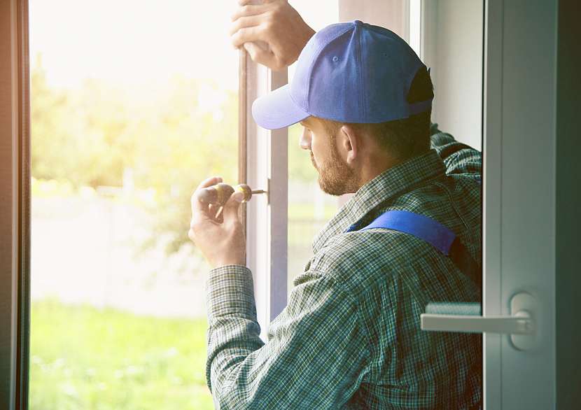 Servisní muž instaluje okno se šroubovákem 